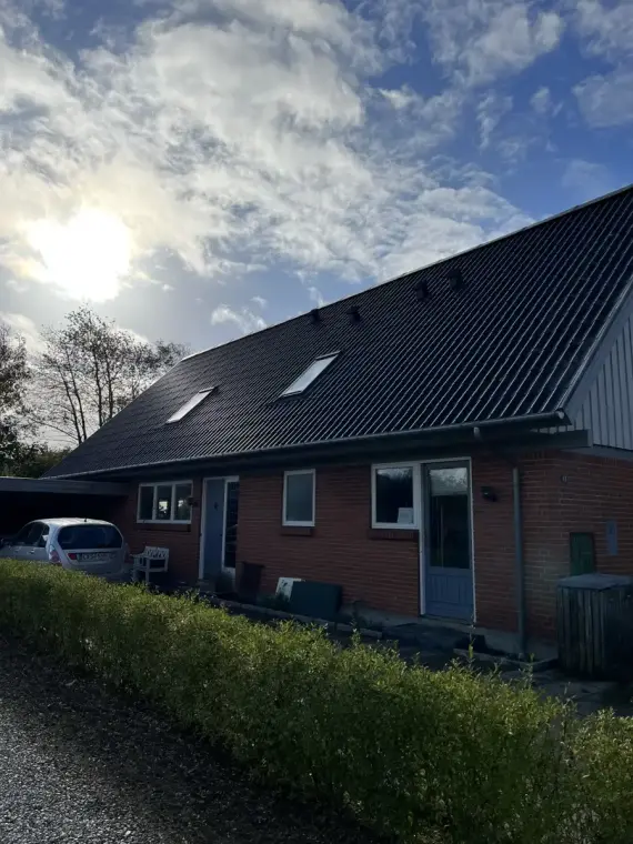 Maison individuelle en brique rouge coiffée d'une toiture neuve en tuiles.